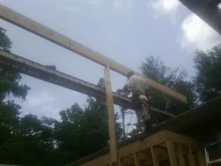 Carpenter setting a ridge beam over a new addition frame — Ice Dam Removal by Roofing Brothers in Johnson City