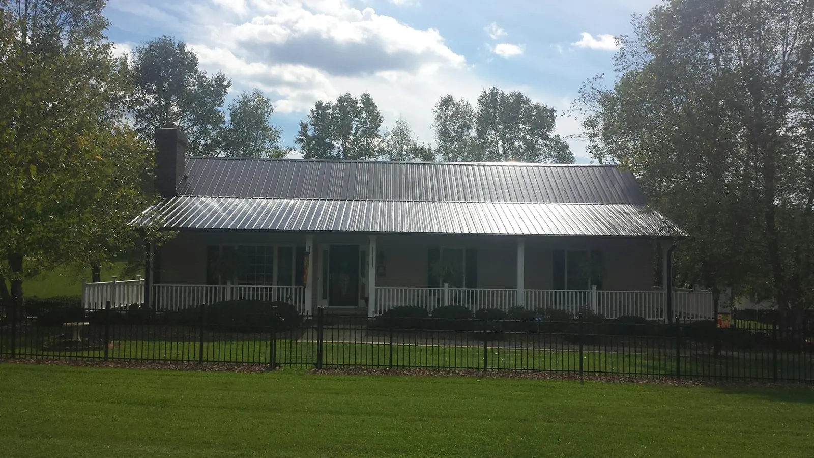 Gray metal roof on a brick ranch with a full width front porch — Gutter Guard Installation work by our crew in Johnson City