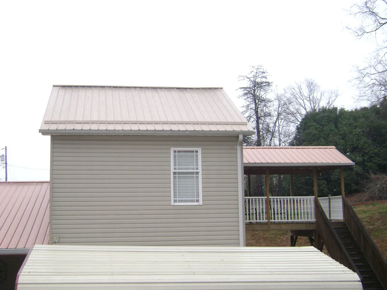 Tan metal roofs on a two story addition and attached porch in Johnson City